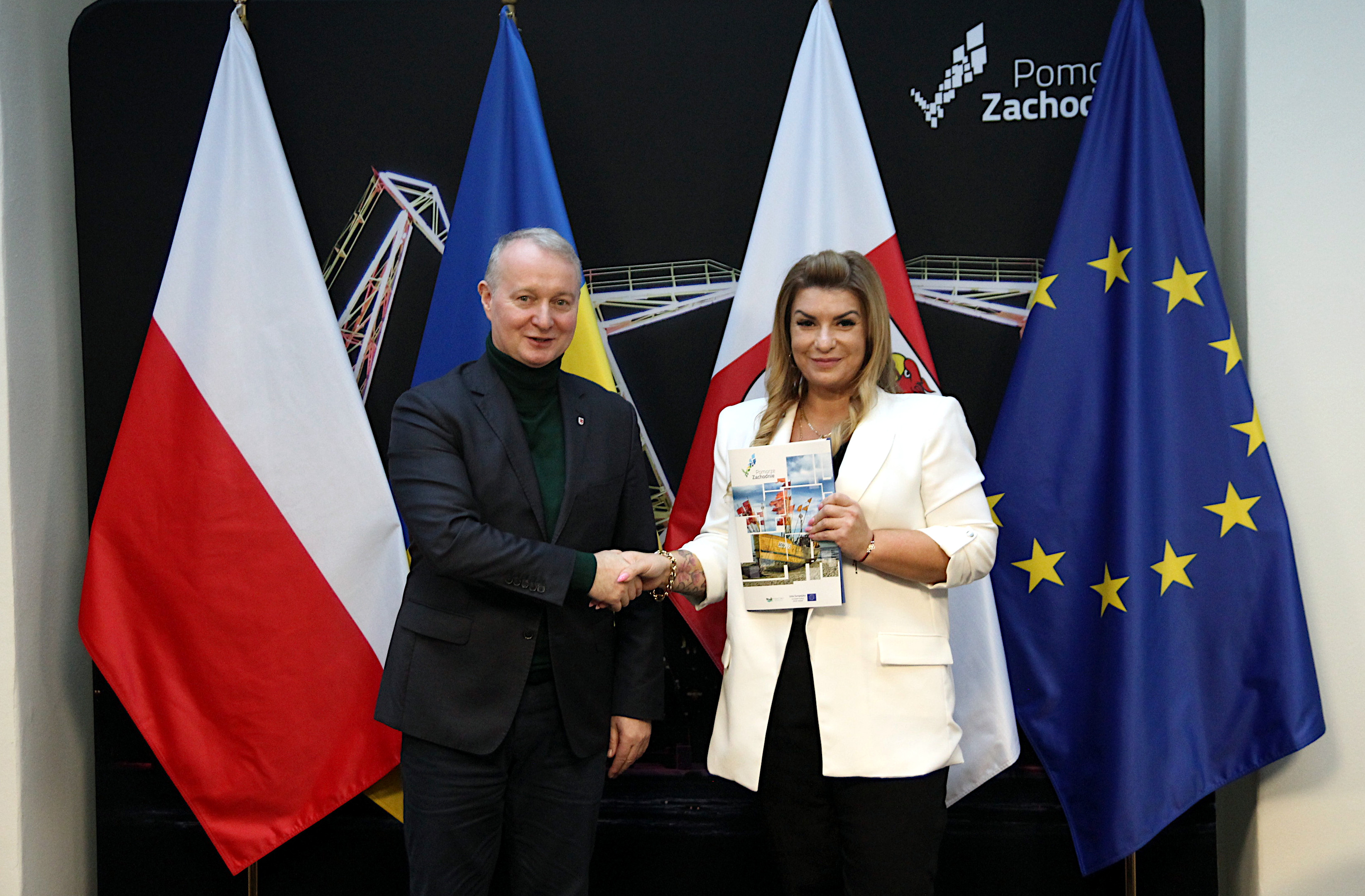 Wicemarszałek Kustosz z beneficjentką na tle promocyjnej ścianki