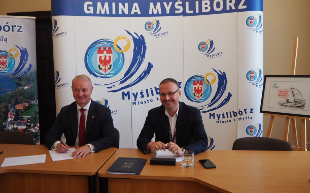 Sygnatariusze składają podpisy na umowie.