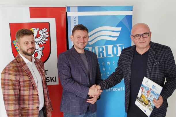 trzech  mężczyzn  na tle kolorowych bannerów 