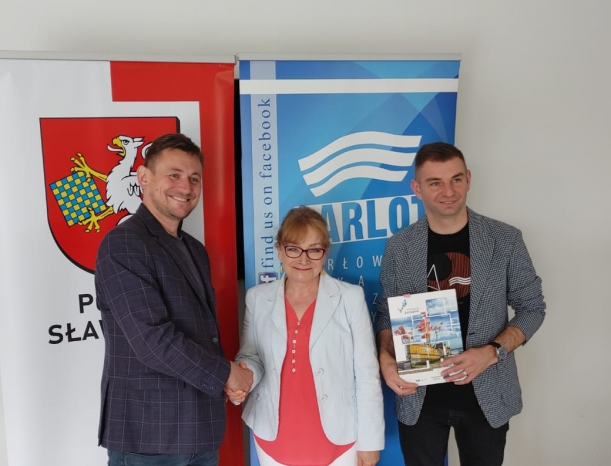 dwóch mężczyzn i jedna kobieta na tle kolorowych bannerów 