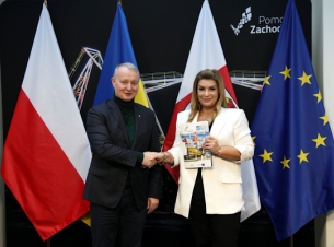 Wicemarszałek Kustosz z beneficjentką na tle promocyjnej ścianki