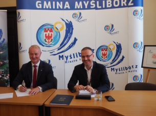 Sygnatariusze składają podpisy na umowie.